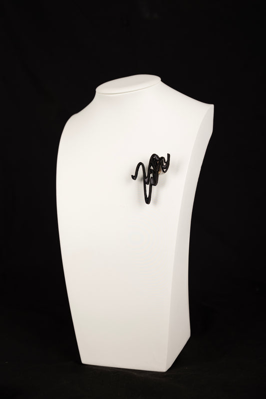 Black wire sculpture on a white rectangular stand against a black background