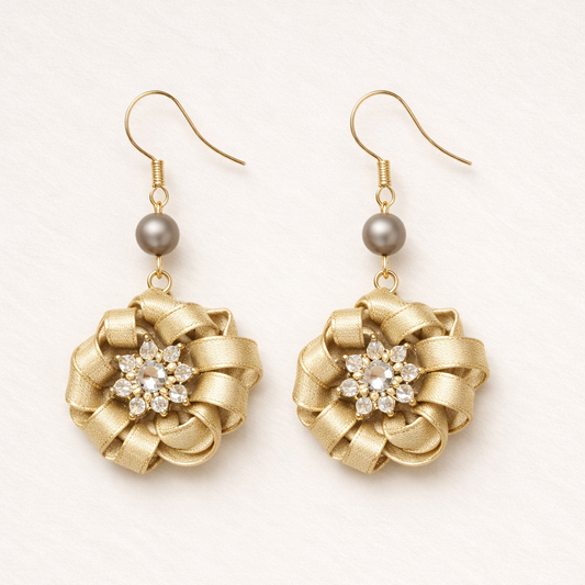 Gold earrings with floral designs and gray beads on a white background