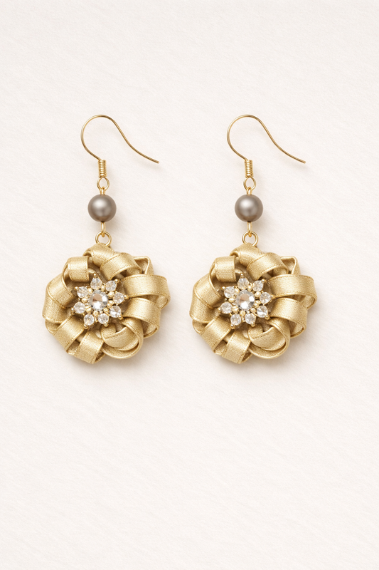 Gold earrings with floral designs and gray beads on a white background