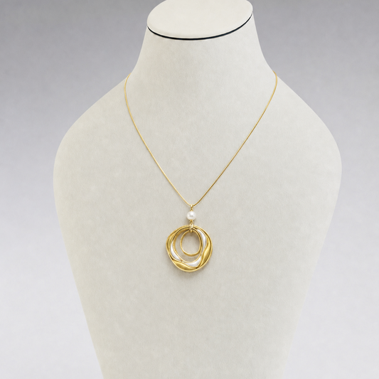 Gold necklace with a pendant on a mannequin bust against a gray background